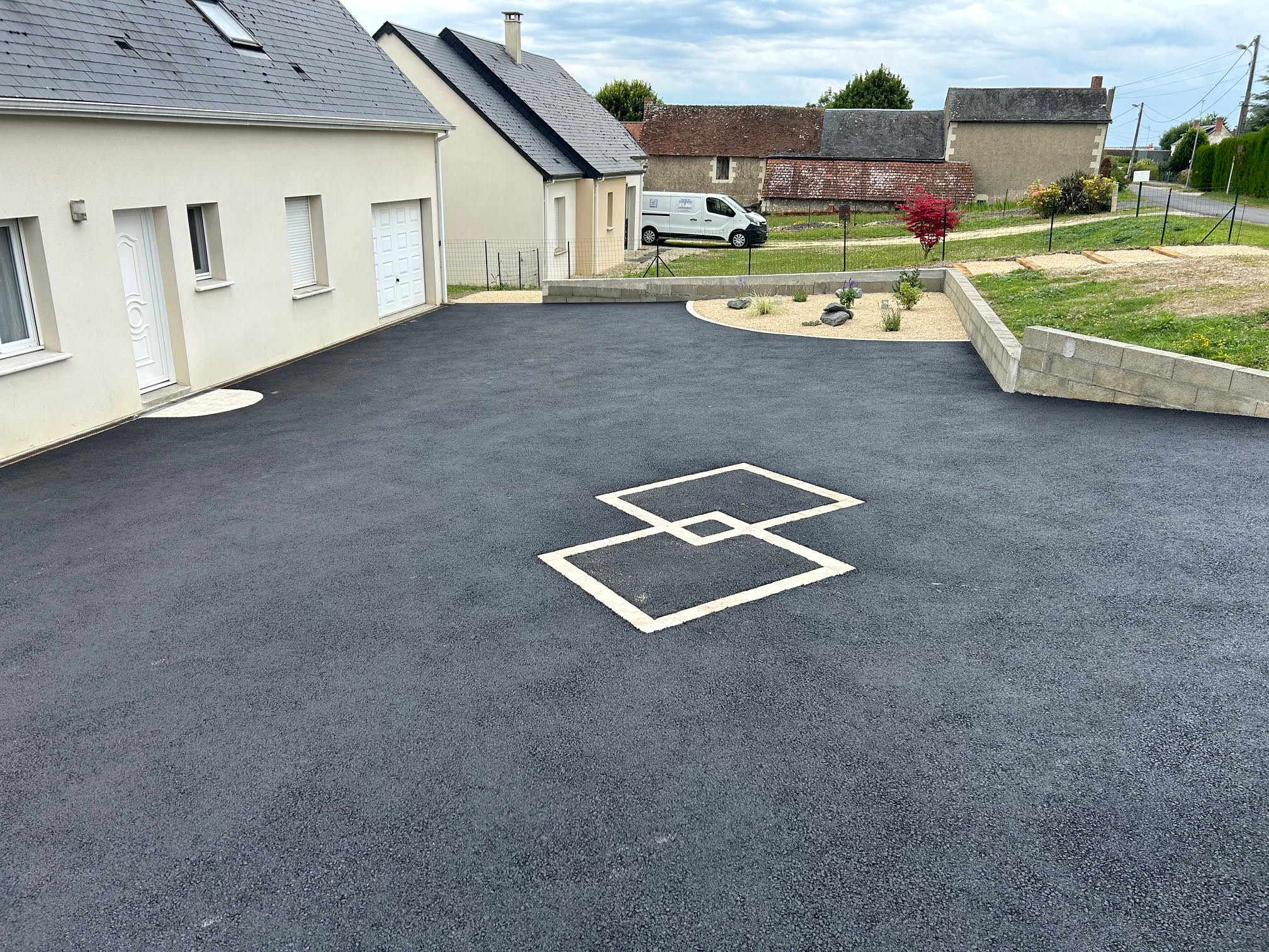 Aménagement extérieur avec pavage devant une maison, incluant une terrasse et une zone en gravier.